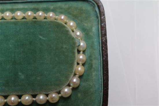 A single strand graduated cultured pearl necklace with an emerald and diamond set white metal clasp, approx. 35cm.